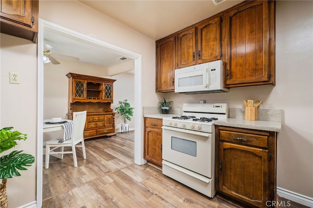 3133 Juanita St, Riverside, CA 92504 - kitchen with white appliances, light countertops, light wood-style flooring, ceiling fan, and brown cabinets