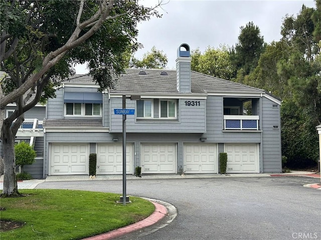 19311 Sunray Ln Unit 104, Huntington Beach, CA 92648 - view of front of house with driveway, a garage, a chimney, and a front yard