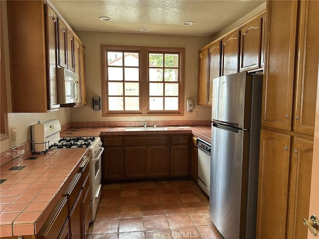 19311 Sunray Ln Unit 104, Huntington Beach, CA 92648 - kitchen with tile counters, white appliances, a textured ceiling, and light tile patterned floors