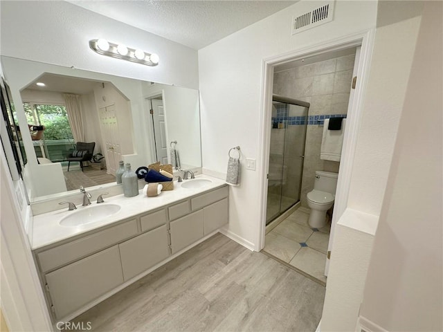 19311 Sunray Ln Unit 104, Huntington Beach, CA 92648 - bathroom with double vanity, a shower stall, wood finished floors, and a textured ceiling