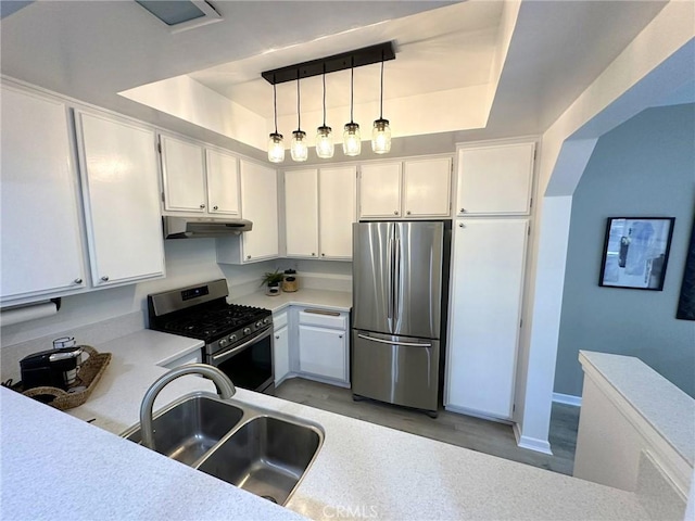 19311 Sunray Ln Unit 104, Huntington Beach, CA 92648 - kitchen featuring appliances with stainless steel finishes, under cabinet range hood, light countertops, a tray ceiling, and white cabinetry
