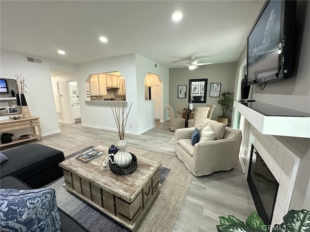 19311 Sunray Ln Unit 104, Huntington Beach, CA 92648 - living room featuring a fireplace, arched walkways, a ceiling fan, light wood-style floors, and recessed lighting
