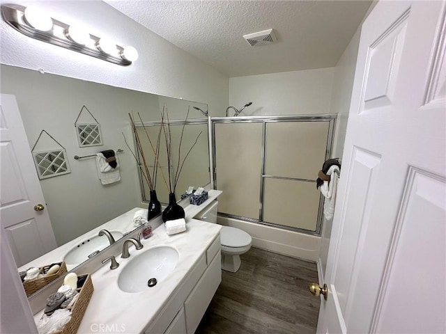 19311 Sunray Ln Unit 104, Huntington Beach, CA 92648 - full bath featuring a textured ceiling, vanity, wood finished floors, and bath / shower combo with glass door