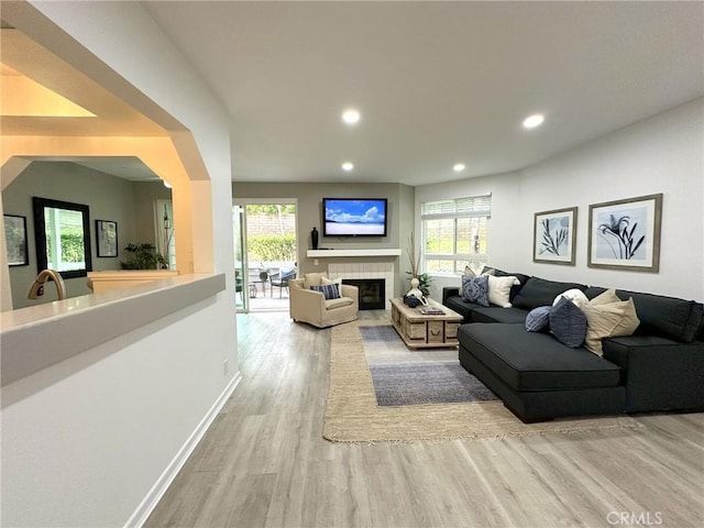 19311 Sunray Ln Unit 104, Huntington Beach, CA 92648 - living area with wood finished floors, recessed lighting, healthy amount of natural light, a tiled fireplace, and arched walkways