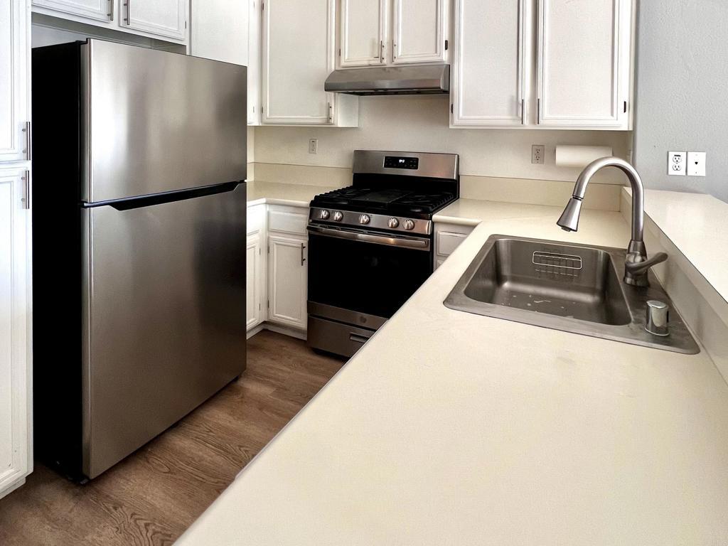 506 62nd St Unit 5, San Diego, CA 92114 - kitchen with stainless steel appliances, under cabinet range hood, dark wood-type flooring, and white cabinetry