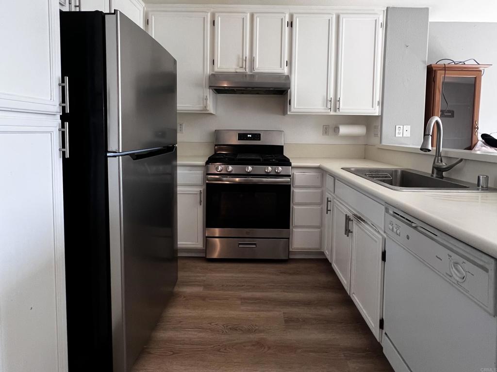 506 62nd St Unit 5, San Diego, CA 92114 - kitchen with stainless steel appliances, under cabinet range hood, white cabinets, and dark wood-style floors