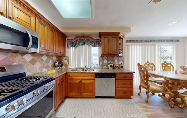 220 S Linhaven Cir, Anaheim, CA 92804 - kitchen featuring stainless steel appliances, brown cabinets, tasteful backsplash, and light stone countertops