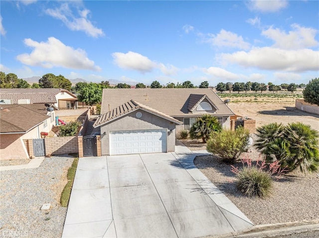 27239 Peach Tree Ln, Helendale, CA 92342 - view of front of home with a gate, concrete driveway, a garage, stucco siding, and a tile roof