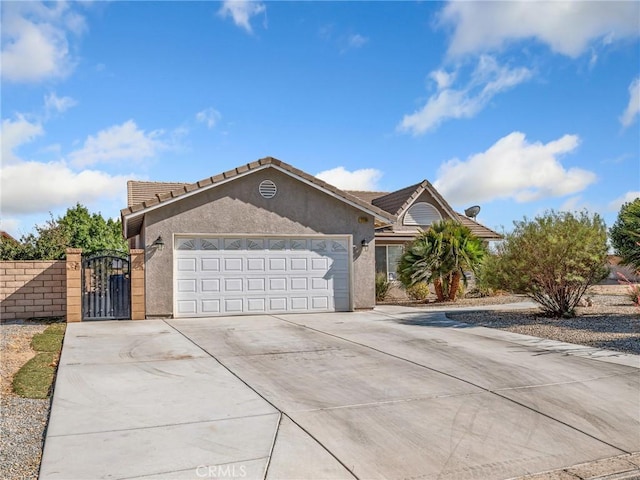 27239 Peach Tree Ln, Helendale, CA 92342 - single story home with concrete driveway, an attached garage, a tile roof, a gate, and stucco siding