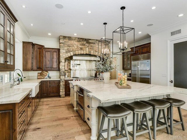 32110 Dos Ninas, Bonsall, CA 92003 - kitchen featuring stainless steel built in fridge, a spacious island, ornamental molding, light wood-style floors, and recessed lighting