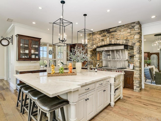 32110 Dos Ninas, Bonsall, CA 92003 - kitchen featuring crown molding, a spacious island, light wood finished floors, wall chimney exhaust hood, and a chandelier