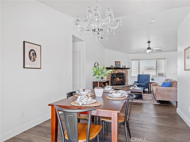 22163 Broken Lance Rd, Apple Valley, CA 92307 - dining room featuring a fireplace, dark wood-type flooring, a chandelier, a ceiling fan, and vaulted ceiling