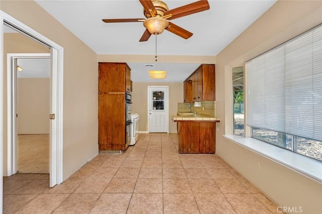 45660 Shain Ave, Dos Palos, CA 93620 - kitchen featuring tile counters, brown cabinets, a ceiling fan, oven, and light tile patterned floors