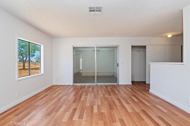 23405 Ramona Ave, Apple Valley, CA 92307 - unfurnished bedroom with multiple closets, a textured ceiling, and light wood finished floors