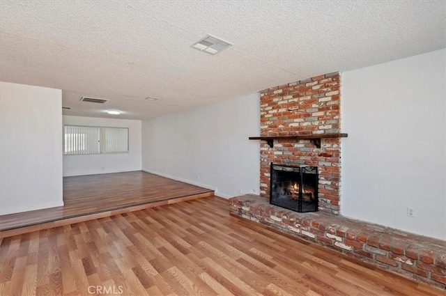 23405 Ramona Ave, Apple Valley, CA 92307 - unfurnished living room featuring wood finished floors, a textured ceiling, and a fireplace