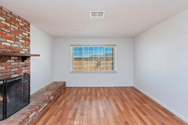 23405 Ramona Ave, Apple Valley, CA 92307 - unfurnished living room with wood finished floors, a fireplace, and a textured ceiling