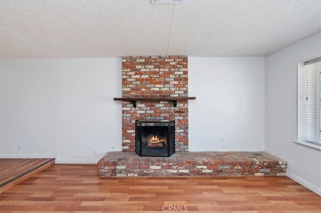 23405 Ramona Ave, Apple Valley, CA 92307 - unfurnished living room featuring wood finished floors, a textured ceiling, and a fireplace