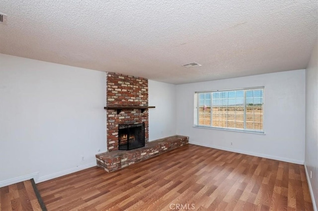 23405 Ramona Ave, Apple Valley, CA 92307 - unfurnished living room featuring wood finished floors, a textured ceiling, and a brick fireplace