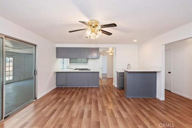 23405 Ramona Ave, Apple Valley, CA 92307 - kitchen with a peninsula, light wood finished floors, a ceiling fan, gray cabinetry, and a textured ceiling