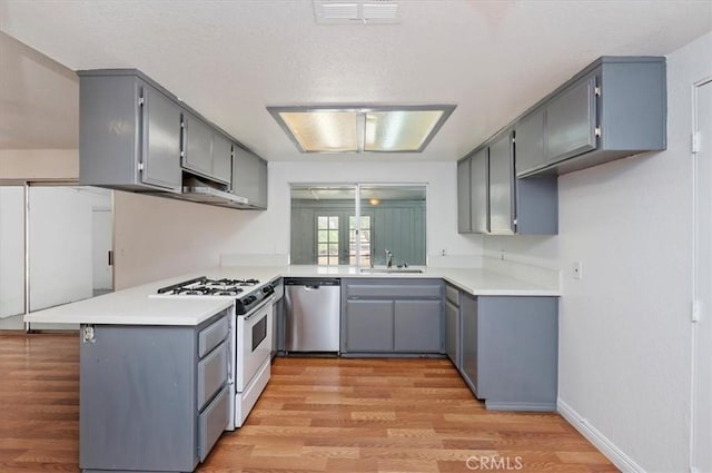 23405 Ramona Ave, Apple Valley, CA 92307 - kitchen with dishwasher, white range with gas stovetop, gray cabinetry, a peninsula, and light wood-style floors