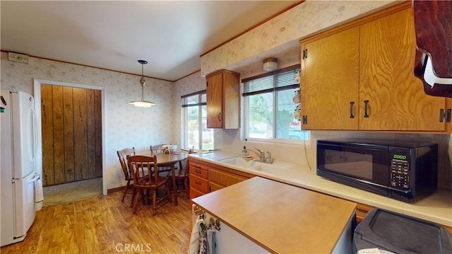 125 Hilton St, Madera, CA 93637 - kitchen with wallpapered walls, black microwave, freestanding refrigerator, light wood-style floors, and light countertops
