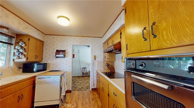 125 Hilton St, Madera, CA 93637 - kitchen with black appliances, light wood-style flooring, light countertops, wallpapered walls, and under cabinet range hood