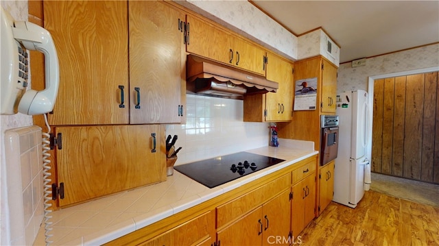 125 Hilton St, Madera, CA 93637 - kitchen featuring under cabinet range hood, freestanding refrigerator, black electric stovetop, oven, and backsplash