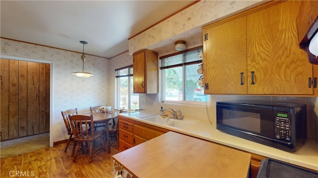 125 Hilton St, Madera, CA 93637 - kitchen with black microwave, wallpapered walls, light wood-style floors, decorative light fixtures, and brown cabinets