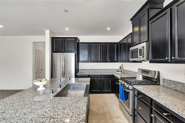 860 Fritz Dr, Los Banos, CA 93635 - kitchen with appliances with stainless steel finishes, dark cabinets, light stone countertops, recessed lighting, and light tile patterned flooring
