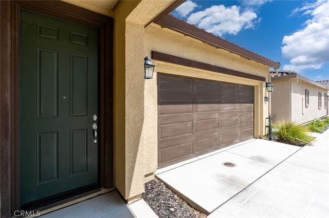 860 Fritz Dr, Los Banos, CA 93635 - view of exterior entry featuring stucco siding, an attached garage, and concrete driveway