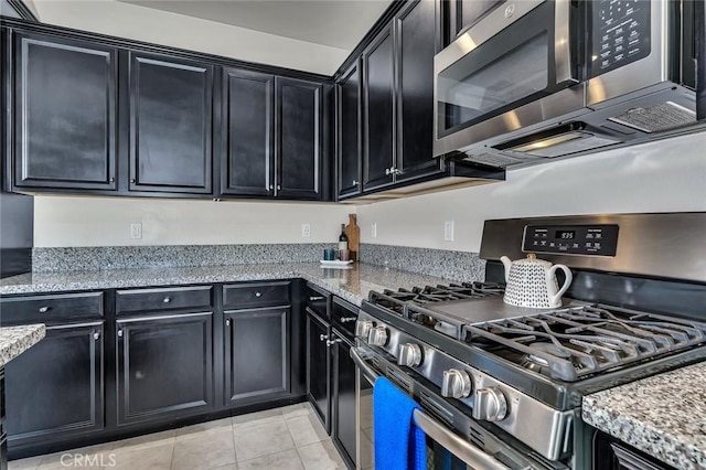 860 Fritz Dr, Los Banos, CA 93635 - kitchen with stainless steel appliances, dark cabinets, light stone counters, and light tile patterned floors
