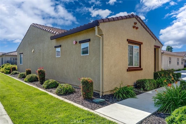 860 Fritz Dr, Los Banos, CA 93635 - view of side of home featuring stucco siding, a lawn, and a tile roof