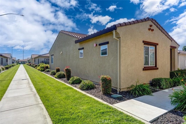 860 Fritz Dr, Los Banos, CA 93635 - view of side of home with stucco siding, a yard, a tiled roof, and a residential view
