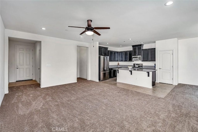 860 Fritz Dr, Los Banos, CA 93635 - kitchen featuring appliances with stainless steel finishes, carpet, open floor plan, a kitchen breakfast bar, and dark cabinets