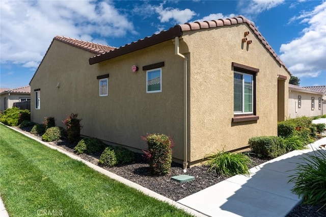 860 Fritz Dr, Los Banos, CA 93635 - view of home's exterior with stucco siding, a tiled roof, and a yard