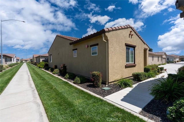 860 Fritz Dr, Los Banos, CA 93635 - view of property exterior featuring stucco siding, a residential view, a yard, and a tile roof