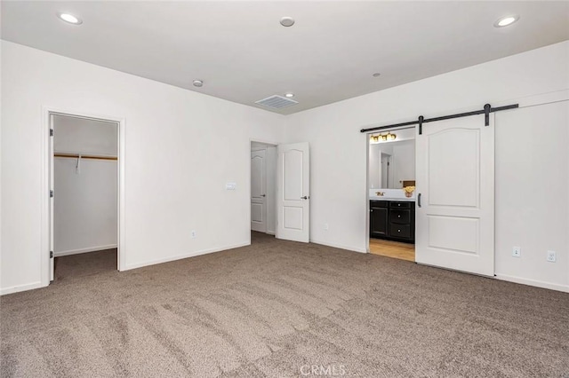 860 Fritz Dr, Los Banos, CA 93635 - unfurnished bedroom with carpet flooring, a barn door, a spacious closet, recessed lighting, and connected bathroom