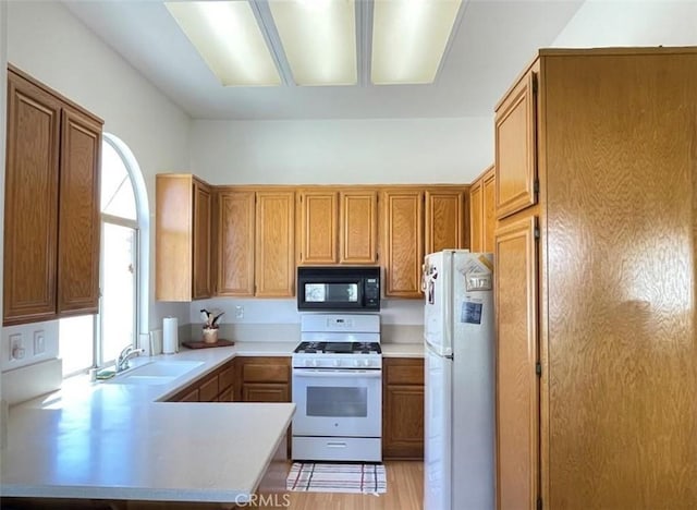 6287 Tuckaway Ave, Banning, CA 92220 - kitchen featuring white appliances, a peninsula, light countertops, and light wood finished floors