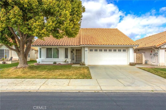 6287 Tuckaway Ave, Banning, CA 92220 - mediterranean / spanish-style house with a tiled roof, concrete driveway, an attached garage, and a front yard