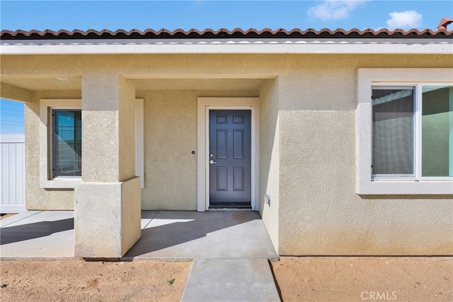 10132 Kemper Ave, Adelanto, CA 92301 - doorway to property featuring stucco siding, a patio area, and a tile roof