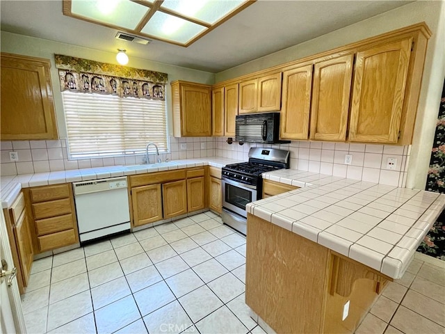 224 Stonewood Dr, Los Banos, CA 93635 - kitchen featuring white dishwasher, stainless steel gas range oven, black microwave, light tile patterned floors, and backsplash