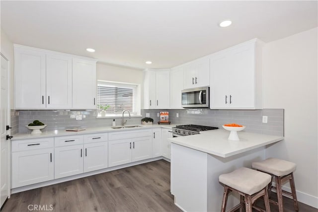 15615 Erie Rd, Apple Valley, CA 92307 - kitchen featuring stainless steel microwave, stove, a breakfast bar area, white cabinetry, and recessed lighting