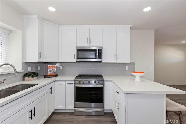 15615 Erie Rd, Apple Valley, CA 92307 - kitchen with appliances with stainless steel finishes, a peninsula, a breakfast bar, dark wood-style floors, and light countertops