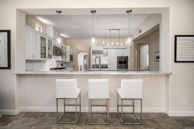 7425 Rancho Cabrillo Trl, San Diego, CA 92127 - kitchen with stainless steel appliances, a peninsula, arched walkways, ventilation hood, and recessed lighting