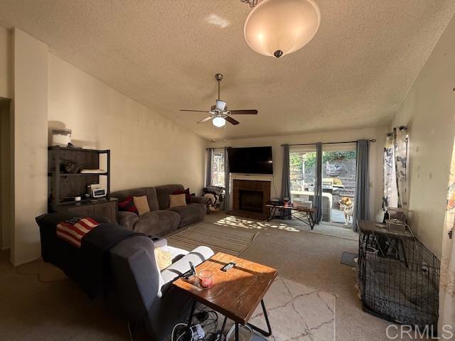 911 Concord Ct, Vista, CA 92081 - carpeted living area with a textured ceiling, ceiling fan, and a fireplace