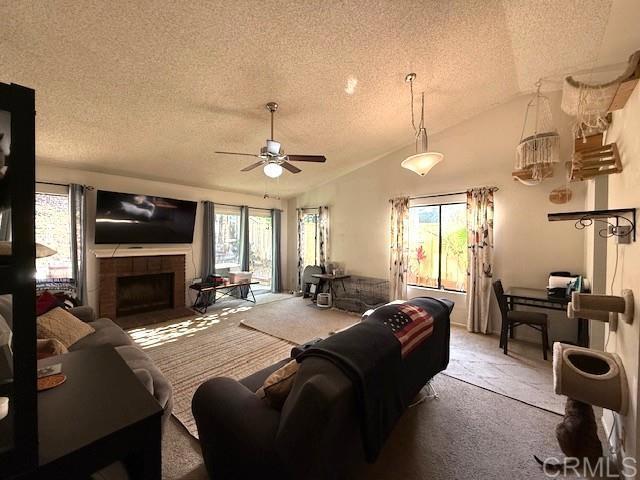 911 Concord Ct, Vista, CA 92081 - living room featuring a textured ceiling, carpet flooring, ceiling fan, a fireplace, and vaulted ceiling
