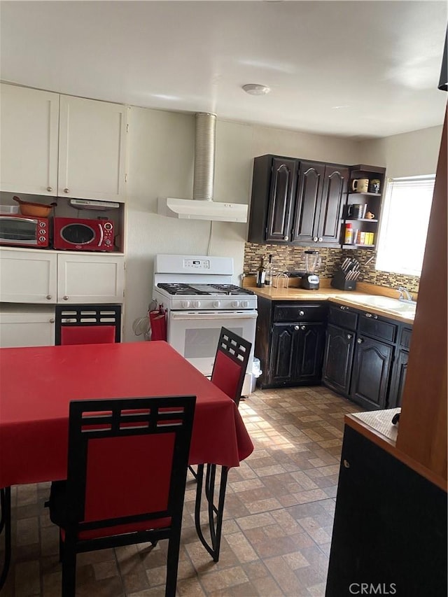 427 W 92nd St, Los Angeles, CA 90003 - kitchen with white gas range oven, open shelves, wall chimney exhaust hood, decorative backsplash, and light countertops