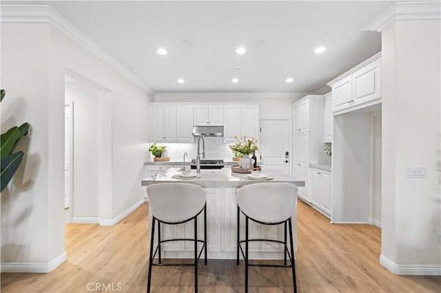 2437 Sanabria Ln, Brea, CA 92821 - kitchen featuring white cabinets, tasteful backsplash, light wood-type flooring, under cabinet range hood, and recessed lighting