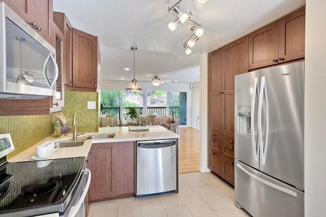 6229 Caminito Basilio, San Diego, CA 92111 - kitchen with appliances with stainless steel finishes, a peninsula, brown cabinetry, backsplash, and open floor plan