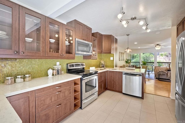 6229 Caminito Basilio, San Diego, CA 92111 - kitchen with appliances with stainless steel finishes, a peninsula, brown cabinetry, light countertops, and backsplash